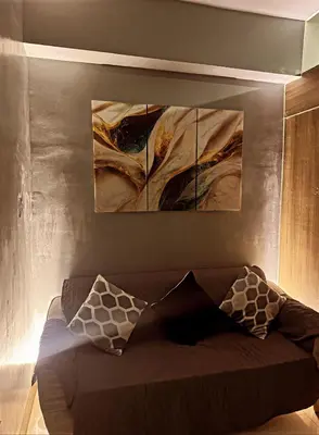 a couch in a room with two paintings on the wall at Fame Residences Mandaluyong 1 BR with two Big TV with Balcony in Manila