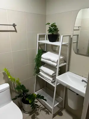 a bathroom with a white shelf with towels and plants at Fame Residences Mandaluyong 1 BR with two Big TV with Balcony in Manila