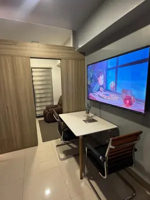 a living room with a table and a large flat screen tv at Fame Residences Mandaluyong 1 BR with two Big TV with Balcony in Manila