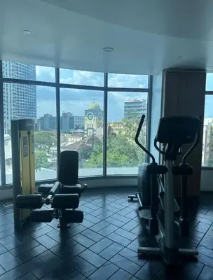 a gym with chairs and a large window in a building at Studio in Eastwood Fast Wifi Free Pool & Gym in Manila