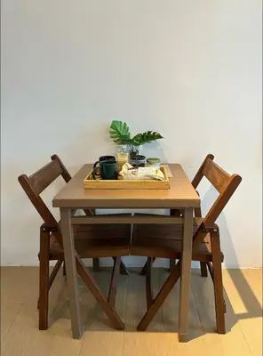 a wooden table with two chairs and a plant on it at Studio in Eastwood Fast Wifi Free Pool & Gym in Manila