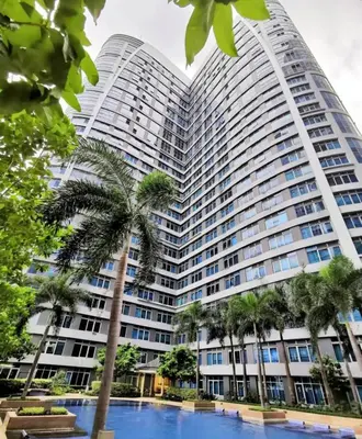 a large building with a palm tree in front of it at Studio in Eastwood Fast Wifi Free Pool & Gym in Manila