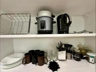 a kitchen shelf with coffee cups and appliances on it at Studio in Eastwood Fast Wifi Free Pool & Gym in Manila