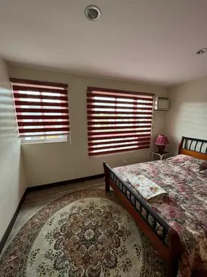 a bedroom with two windows and a bed and a rug at bendetto residences in Manila