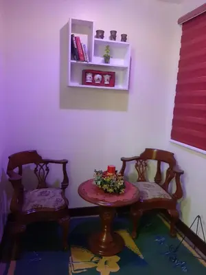 a room with two chairs and a table with flowers on it at bendetto residences in Manila