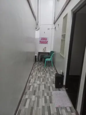a hallway with a table and a green chair at Joshua Transient in Manila
