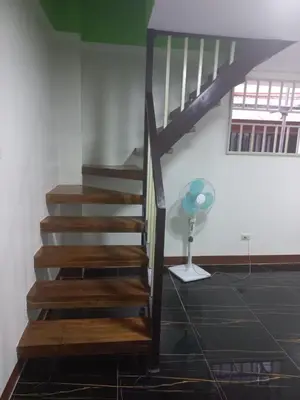 a wooden staircase in a room with a fan at Joshua Transient in Manila
