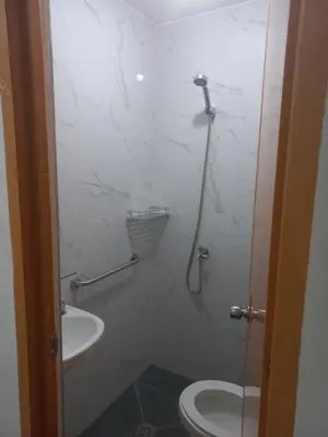 a bathroom with a shower with a toilet and a sink at Joshua Transient in Manila