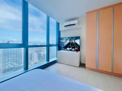 a bedroom with a tv and large windows at One Uptown Residence BGC in Manila