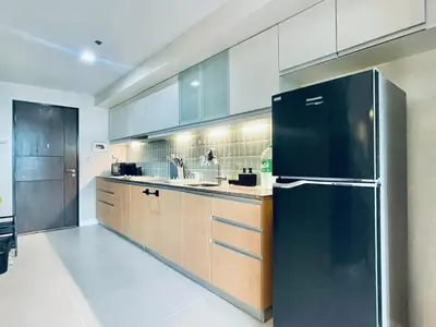 a large kitchen with a black refrigerator in it at One Uptown Residence BGC in Manila