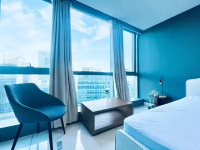 a bedroom with a bed and a chair and a large window at One Uptown Residence BGC in Manila