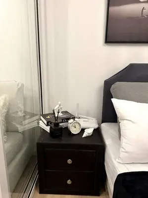 a nightstand with a clock on it next to a bed at El Spacio Azure 1BR with PS4 & Netflix in Manila
