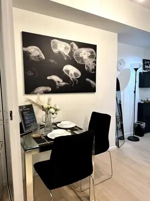 a dining room with a table with chairs and a picture of birds at El Spacio Azure 1BR with PS4 & Netflix in Manila