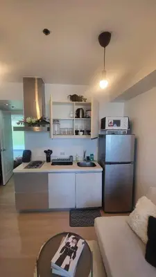 a kitchen with a refrigerator and a table in a room at El Spacio Azure 1BR with PS4 & Netflix in Manila