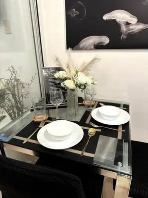 a table with two white plates and a vase with flowers at El Spacio Azure 1BR with PS4 & Netflix in Manila