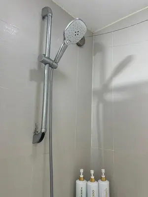 a shower head in a bathroom with three bottles at Affordable Azure Staycation in Manila