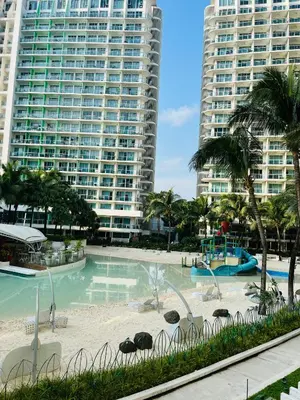 a swimming pool with chairs and palm trees and buildings at Casa Marix & Z - Beach View Unit in Manila