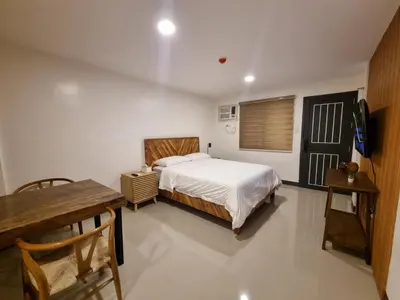 a bedroom with a bed and a table and a television at Flat 35, Unit 1E in Manila