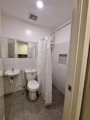 a white bathroom with a toilet and a sink at Flat 35, Unit 1E in Manila