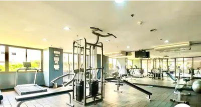 a gym with cardio equipment in a room with windows at 20C Staycation away from home in Manila