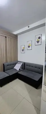 a living room with a black couch and pictures on the wall at STAYCATION near MOA in Manila