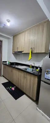 a kitchen with a sink and wooden cabinets at STAYCATION near MOA in Manila