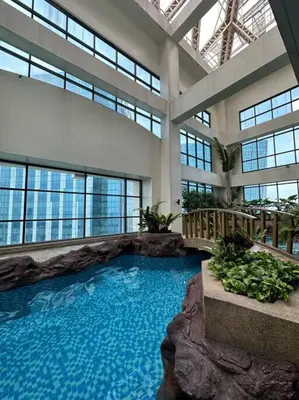 a large swimming pool in a building with windows at 1br wNetflix Disneyplus and pool across SM Megamall Ortigas CBD in Manila