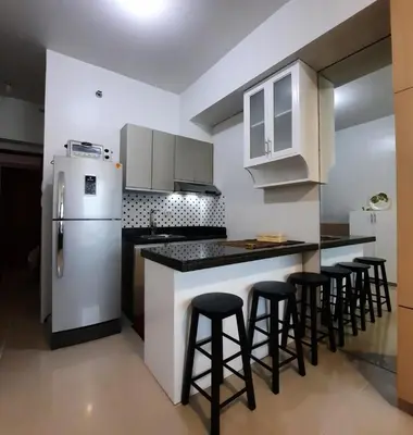 a kitchen with a white refrigerator and some bar stools at Quaint Aparthotel T22306 in Manila