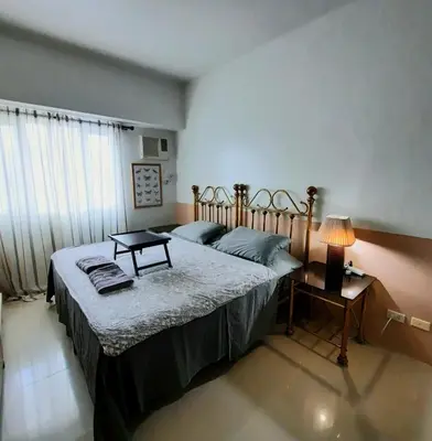 a bedroom with two beds and a table and a lamp at Quaint Aparthotel T22306 in Manila