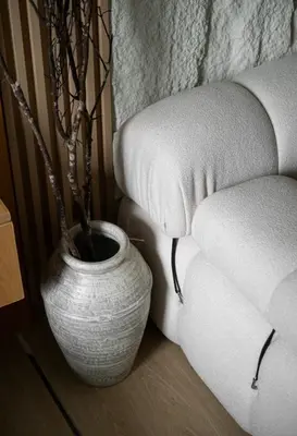 a white vase with a plant in it next to a couch at Sarannya Home BGC in Manila