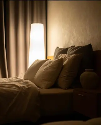 a bedroom with a bed with pillows and a lamp at Sarannya Home BGC in Manila