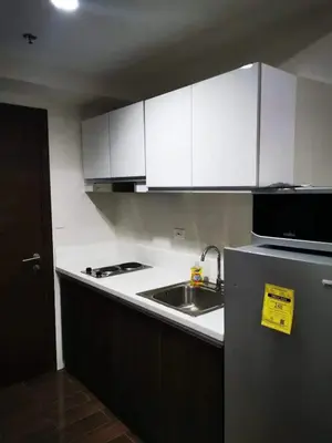 a kitchen with white cabinets and a sink and a microwave at Air Residences - Panoramic City View near Airport - 4734 in Manila