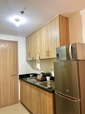 a kitchen with a stainless steel refrigerator and wooden cabinets at Jen staycation in Manila