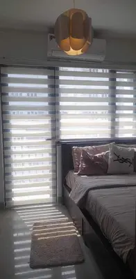 a bedroom with a bed and a large window with blinds at Jen staycation in Manila