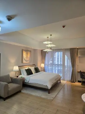 a large bedroom with a bed and a couch at Minimalist and cozy place with balcony in Manila