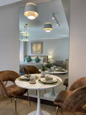 a living room with a table and chairs and a bed at Minimalist and cozy place with balcony in Manila