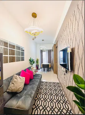 a living room with a couch and a tv at Cosy Deluxe Flat with Balcony near MOA in Manila
