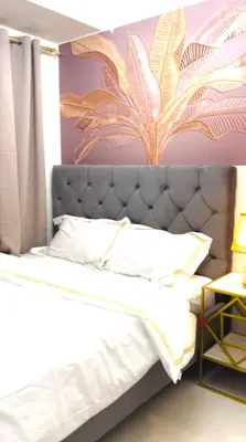 a bedroom with a bed with a large flower on the wall at Cosy Deluxe Flat with Balcony near MOA in Manila