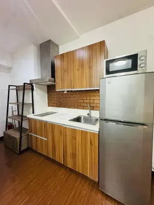 a kitchen with a stainless steel refrigerator and wooden cabinets at Makati City Studio with Balcony Near Bgc And Airport in Manila