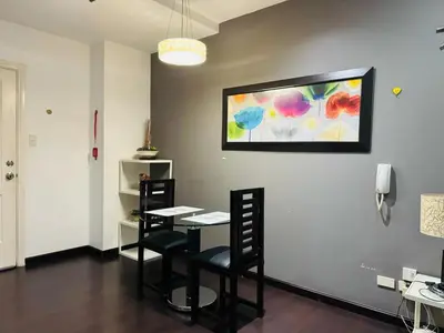 a room with a table and chairs and a painting on the wall at Makati City Studio with Balcony Near Bgc And Airport in Manila