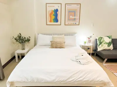a large white bed in a room with a couch at Stylish Condo, Venice BGC, Pool, WiFi #vlrtc29e in Manila