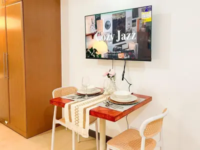 a dining room table with chairs and a tv on the wall at Modern BGC Stay at Venice Residences #vlrtc29h in Manila