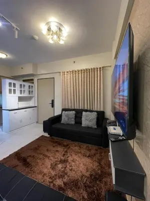 a living room with a black couch and a flat screen tv at Mirea Residences Pasig- Two Bedroom Condo Unit with Balcony 70sqm in Manila