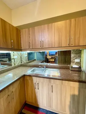a kitchen with wooden cabinets and a sink at Mirea Residences Pasig- Two Bedroom Condo Unit with Balcony 70sqm in Manila
