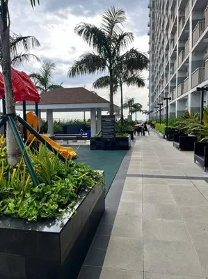 a resort with a playground and palm trees and a building at Coast Residence Sea View Balcony Netflix WiFi Near MOA 3146 in Manila
