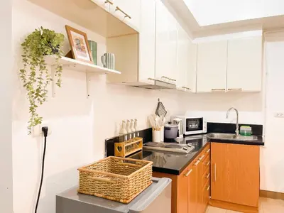 a kitchen with white cabinets and a basket on the counter at Cozy Condo in Venice BGC with balcony #vlrtc28C in Manila