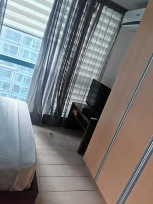 a room with a bed and a window and a desk at One Uptown Residence in Manila