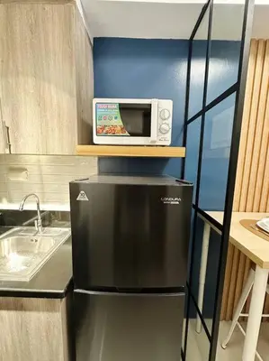 a kitchen with a microwave on top of a refrigerator at The W Place in Manila
