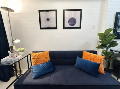 a black couch with orange and blue pillows in a room at The W Place in Manila