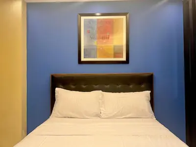a bed with a blue wall and a picture above it at 7H Kiel Hotel NAIA Terminal 3 in Manila